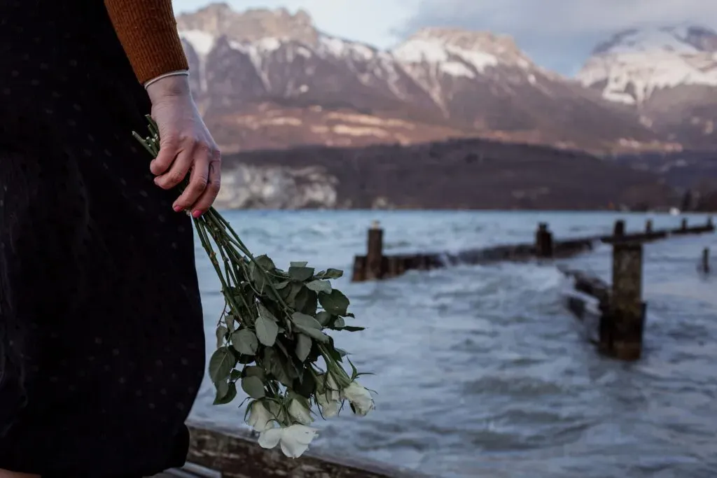 Recueillement avec bouquet roses blanches face au lac d'Annecy.
